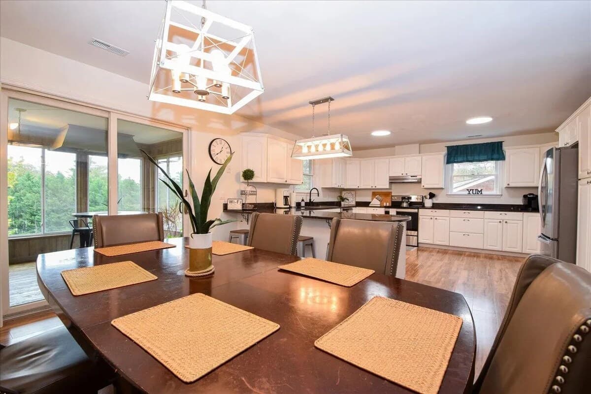 
Family-style dining for 6-8 (extra chairs in pantry behind table)— open to the kitchen, steps from the sunroom. Seats 6-8, dining table, open-concept, cage chandelier, sunroom access, family dining, open floor plan, lake house dining. 