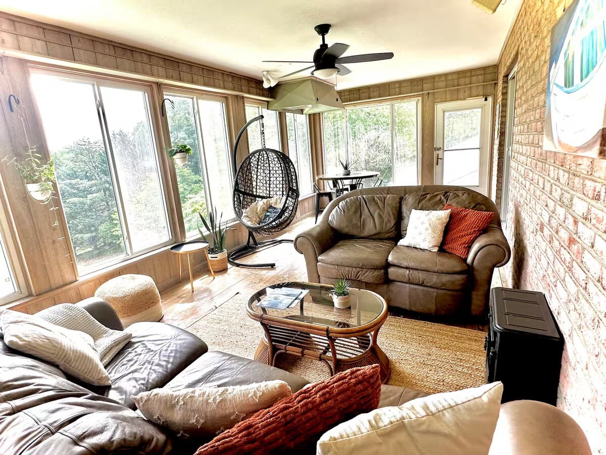 Enclosed and Climate Controlled Sunroom with lake views — our guests' favorite spot.
Sunroom, wraparound windows, lake views, hanging egg chair, ceiling fan, wicker sectional, cedar-paneled, cozy retreat, nature views, Smith Mountain Lake.