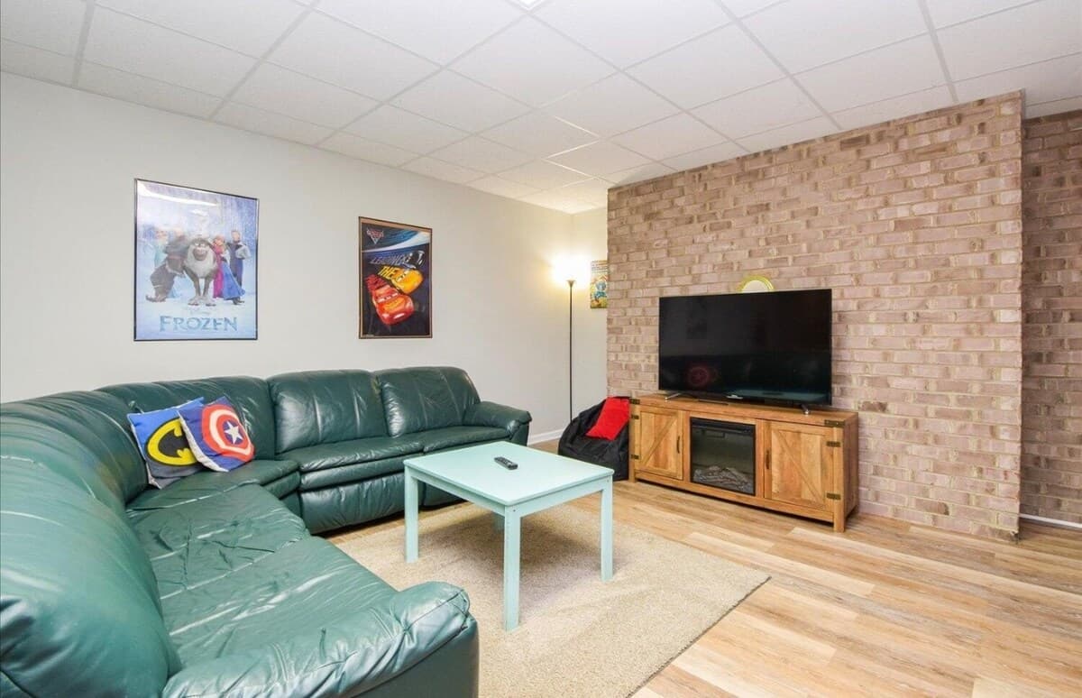 TV lounge with video games & consoles — part of the open lower-level fun zone.

video games, gaming consoles, flat-screen TV, lounge, kids' movies, family-friendly, brick accent wall, electric fireplace, lower-level fun zone, rainy day entertainment.