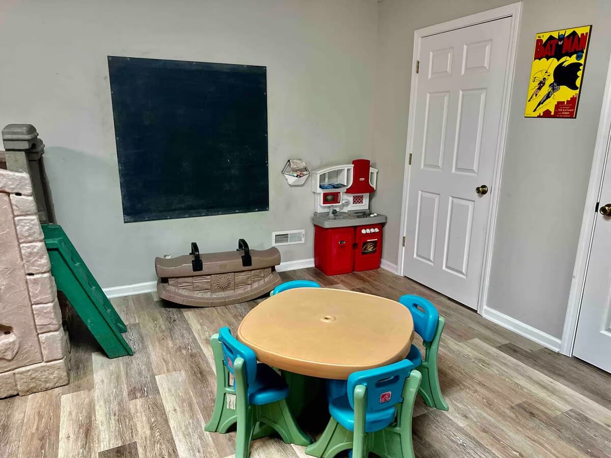 Kids' play area opens straight into the game room rain or shine— everyone hangs out together.

children's toys, play kitchen, castle slide, chalkboard wall, toddler-friendly, kid-friendly, family rental, multigenerational, lake house with kids.
