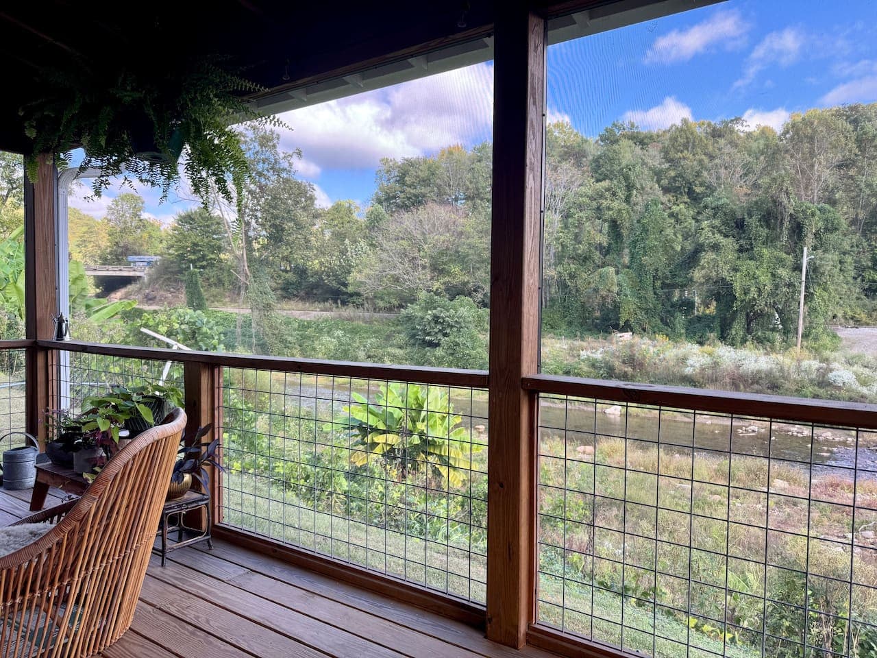 Porch seating with tranquil creek and green backdrop.