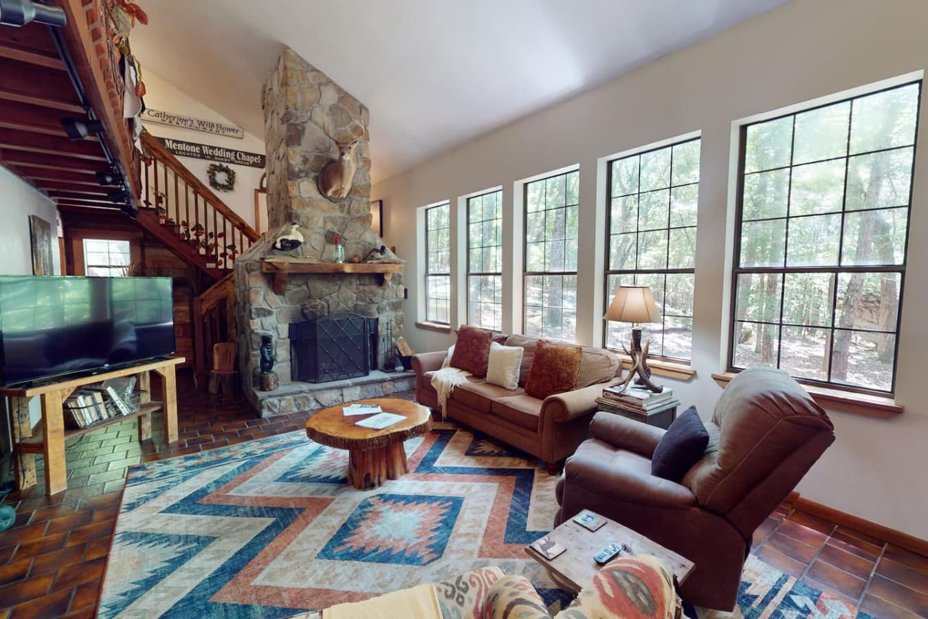 Gather in the inviting living room featuring a cozy gas fireplace and rustic stone walls.