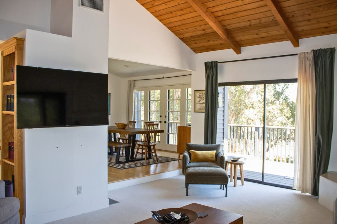 Bright and airy living room with large windows and glass sliding doors leading to the expansive deck. Relax and unwind with a 65" smart TV and stunning lake views.