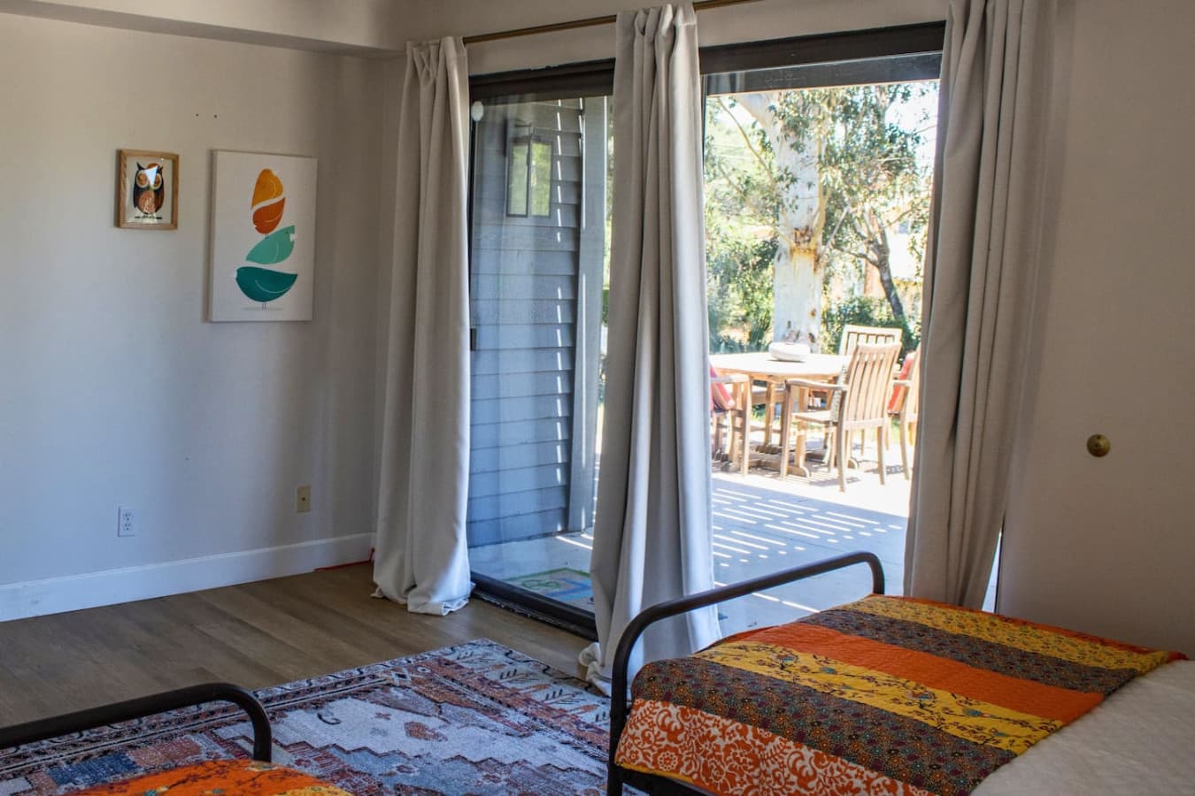 Charming first-floor bedroom with two twin beds, sliding doors to the porch, and an en-suite bathroom with a shower and tub, providing a comfortable and private space.