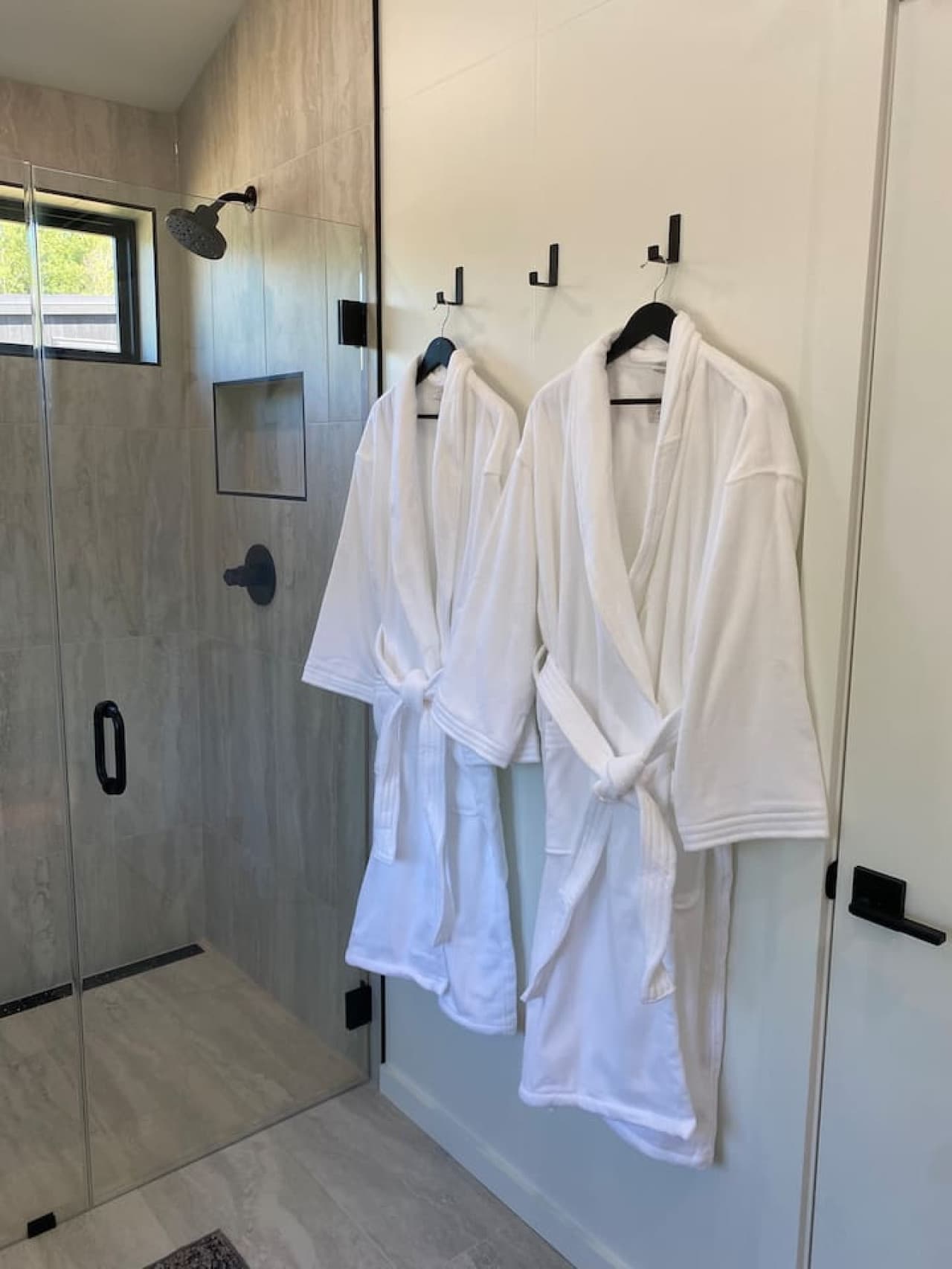 Enjoy a sleek, separate shower with fresh towels and essentials for a refreshing coastal start to your day.