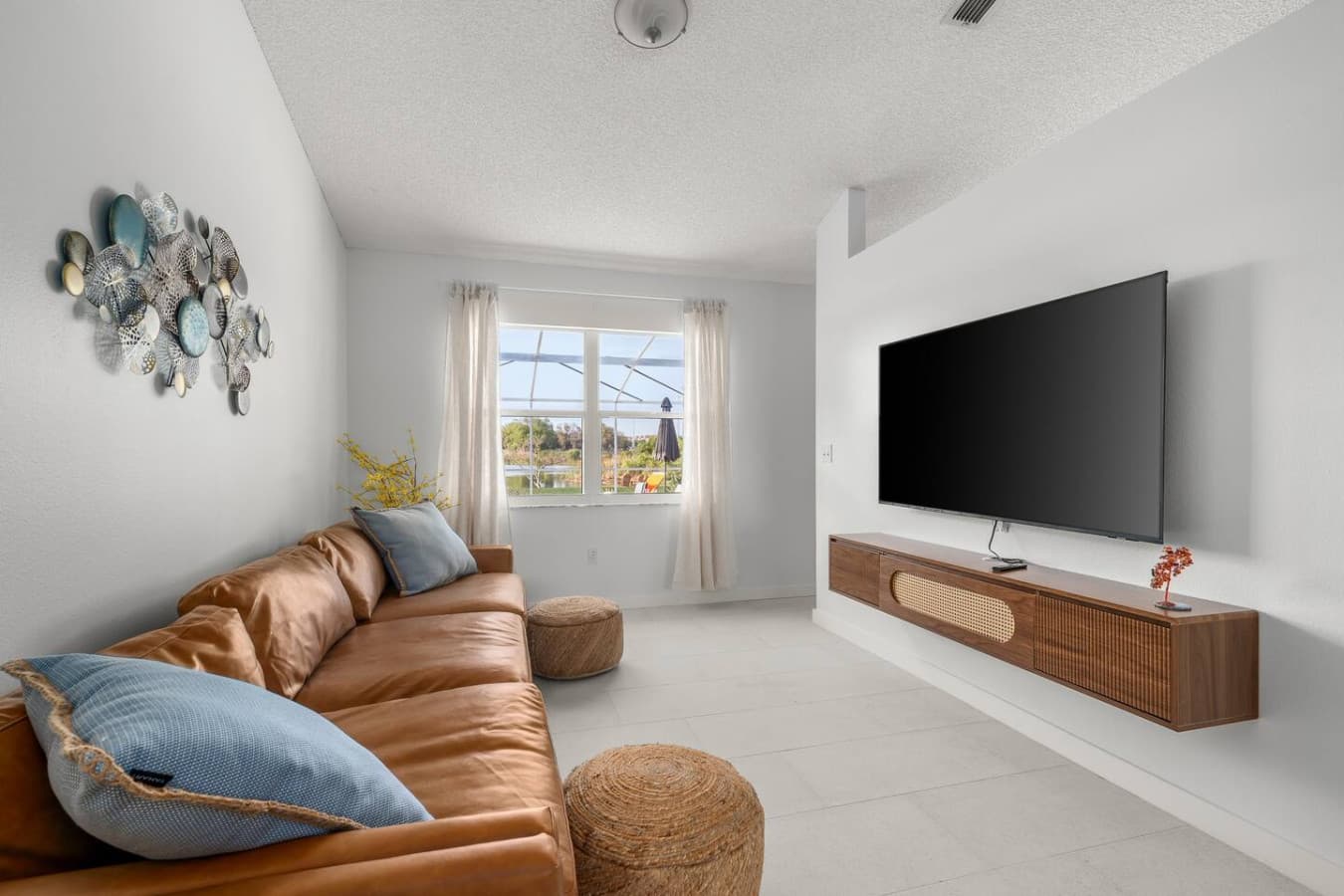Spacious lounge with warm natural light, comfy leather seating, and a TV to relax in style.