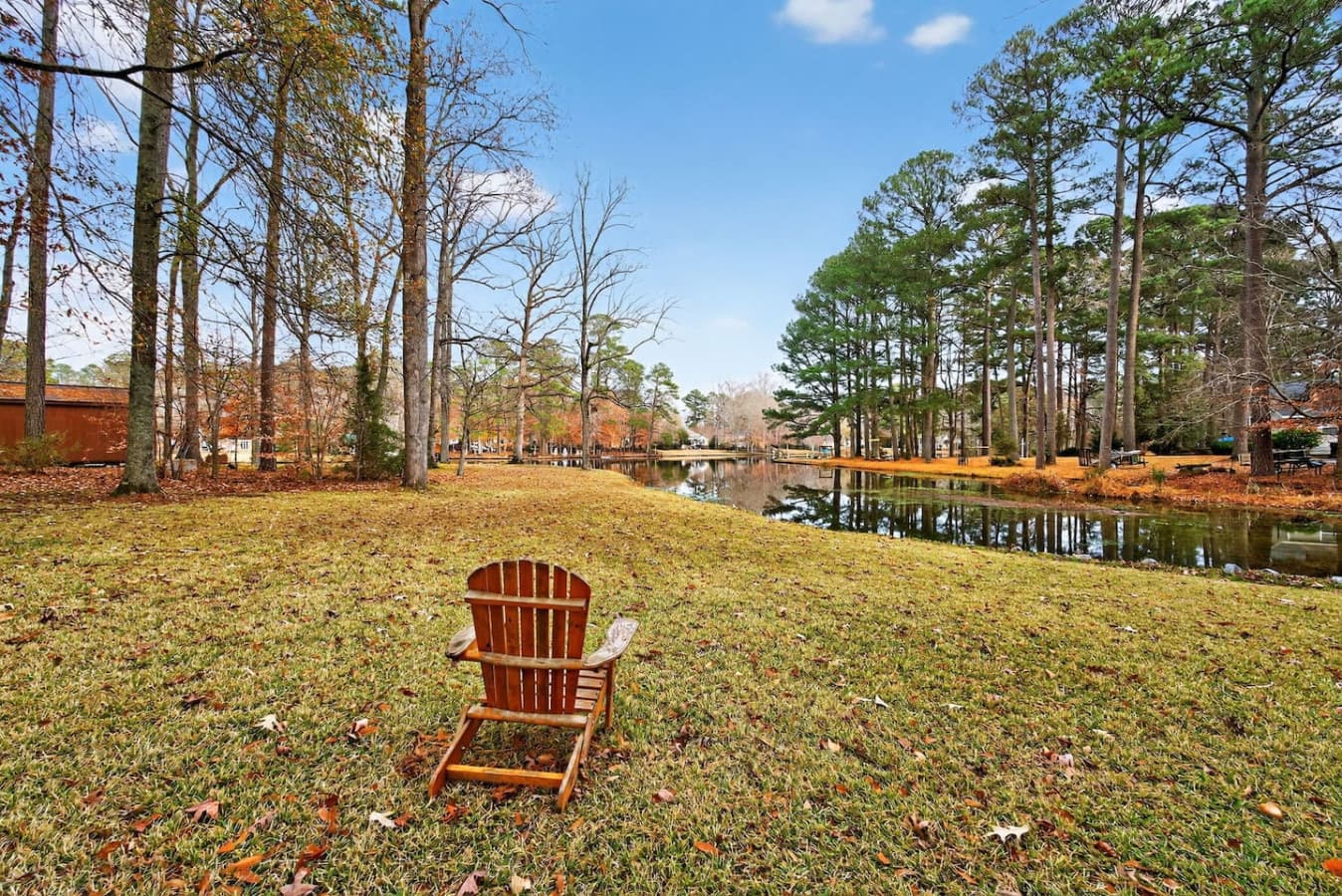Outdoor seating overlooking the peaceful lake, surrounded by mature trees and open green space—perfect for relaxing or enjoying the view.