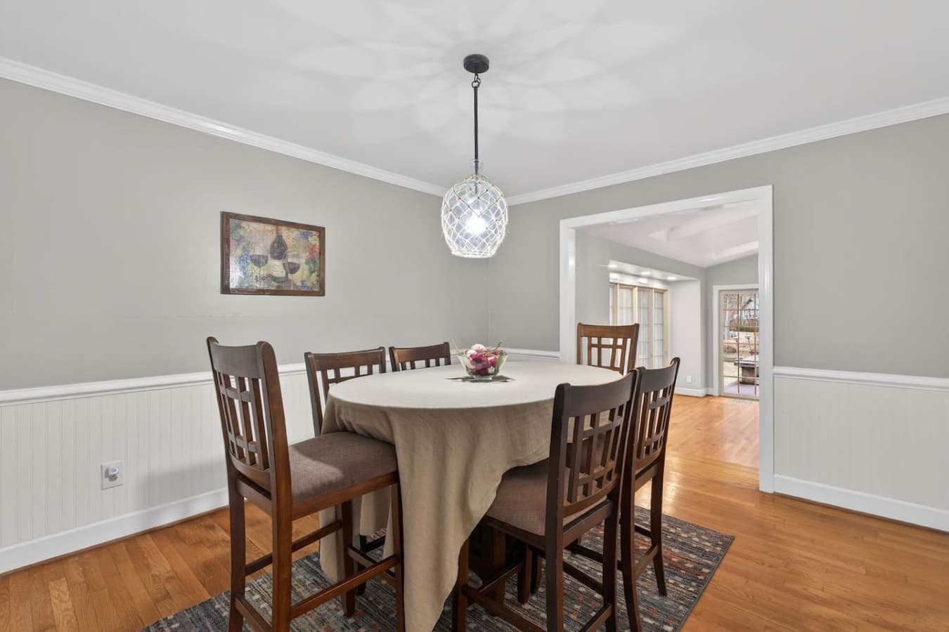 Cozy dining room accented by soft neutral tones, wood flooring, and a stylish overhead light—ideal for gatherings big or small.