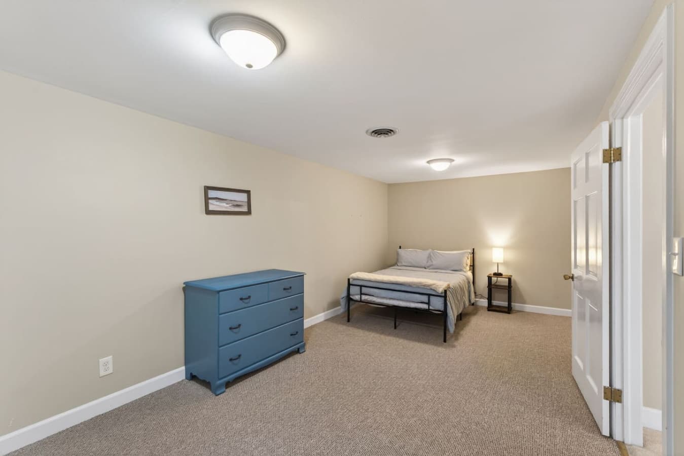 Bedroom furnished with a full bed and spacious blue dresser, offering a comfortable layout and plenty of room to settle in.