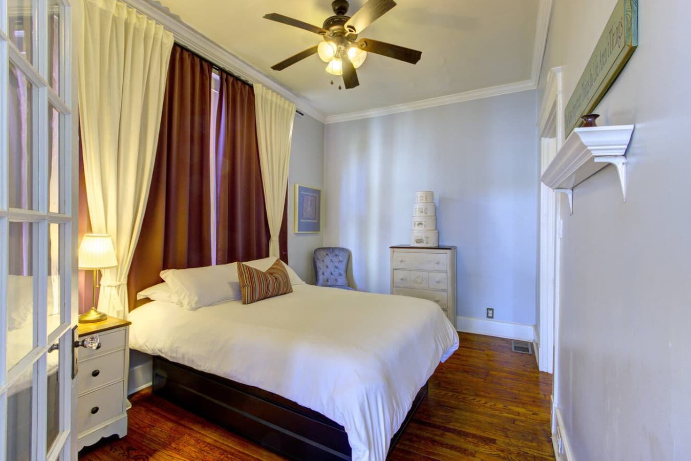 Bedroom 2 with queen bed, tall windows, and ceiling fan for comfort.