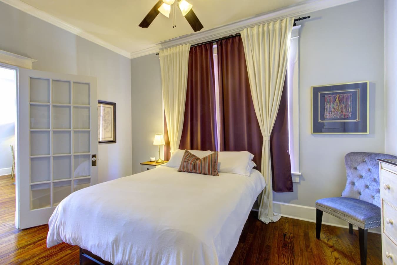 Bedroom 2 with queen bed, tall windows, and ceiling fan for comfort.