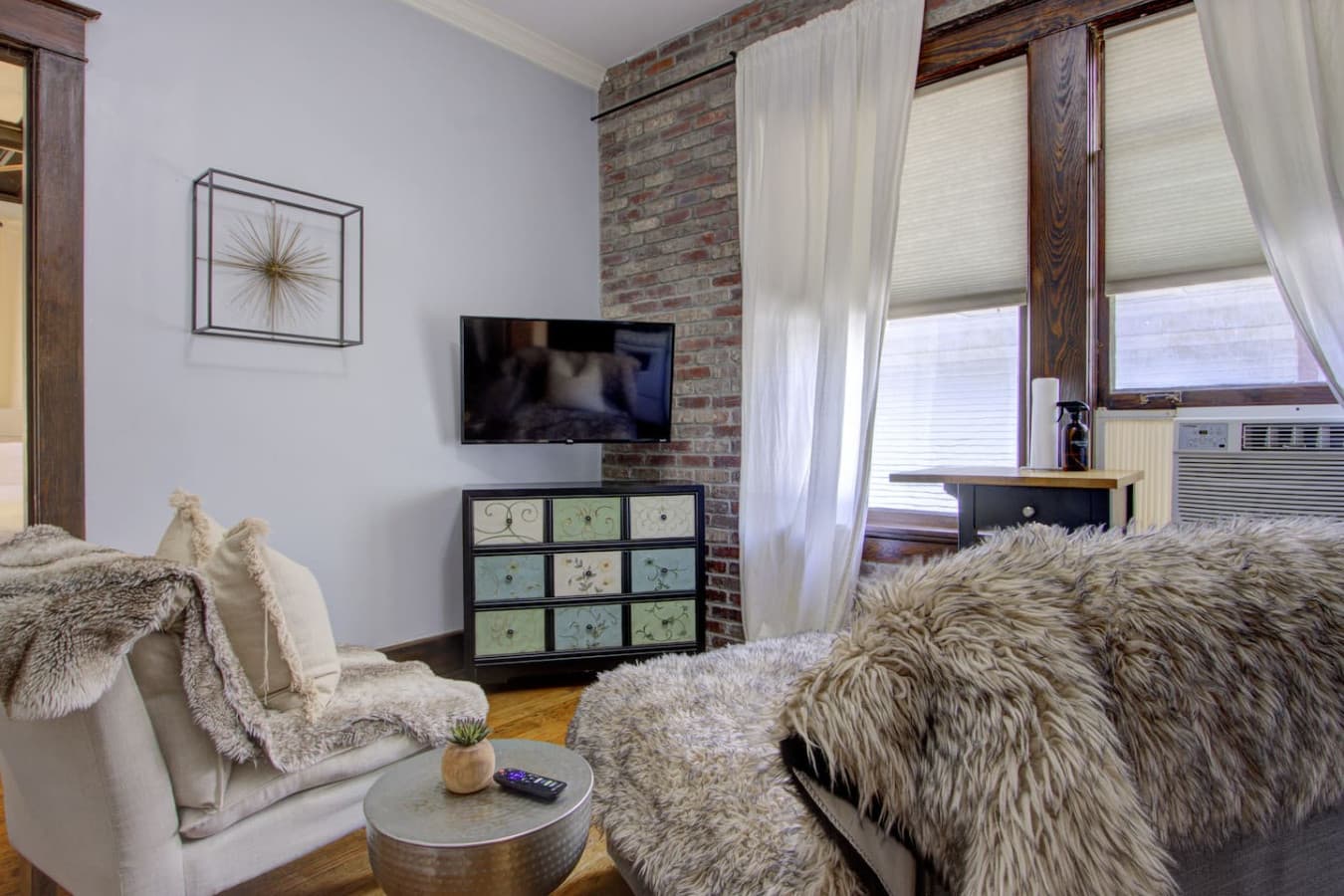 Cozy living area with exposed brick, natural light, and a comfy seating nook, perfect for relaxing with a movie or enjoying a quiet evening after exploring Midtown.