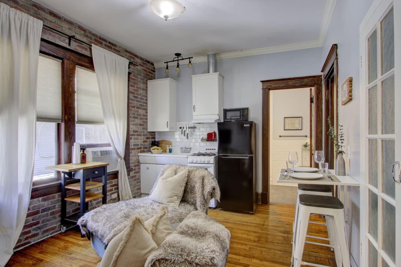 View from the bedroom into the bright living area, with the bathroom just beyond, showcasing the apartment’s open flow and charming historic details.