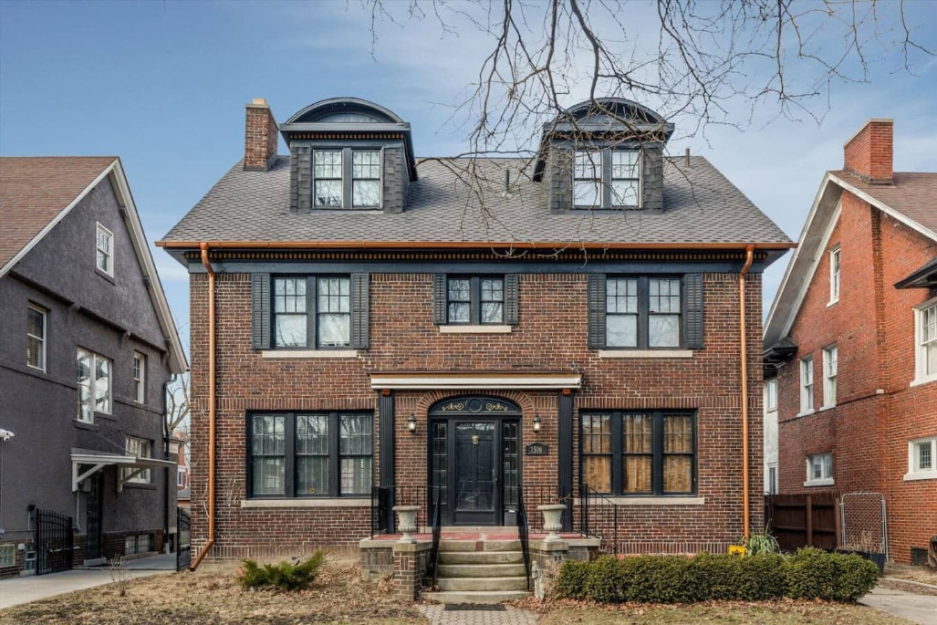 A grand historic home spread across three levels, surrounded by lush greenery and rich in old-world charm.