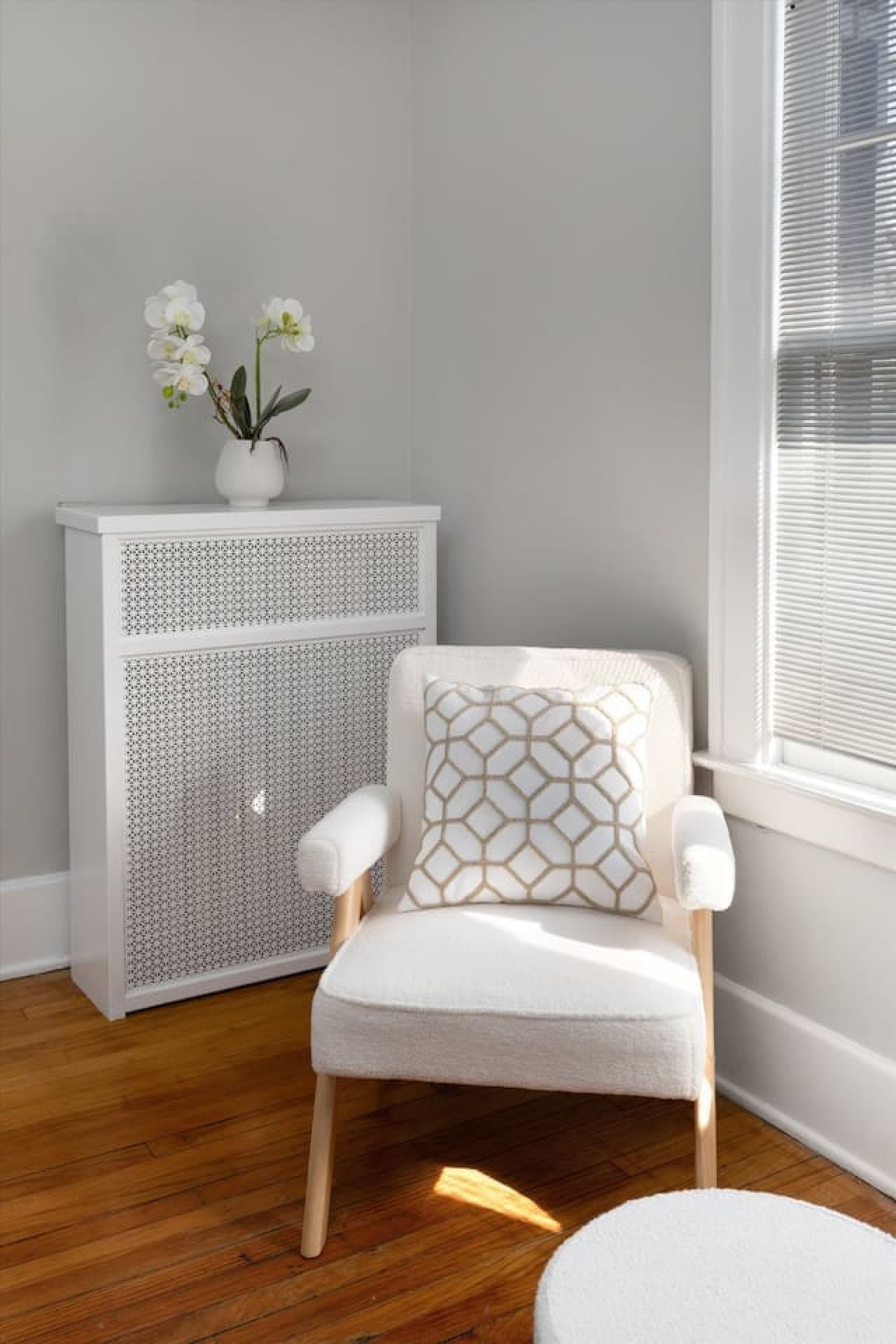 Light pours in over a queen bed, complemented by small white armchairs for extra comfort.