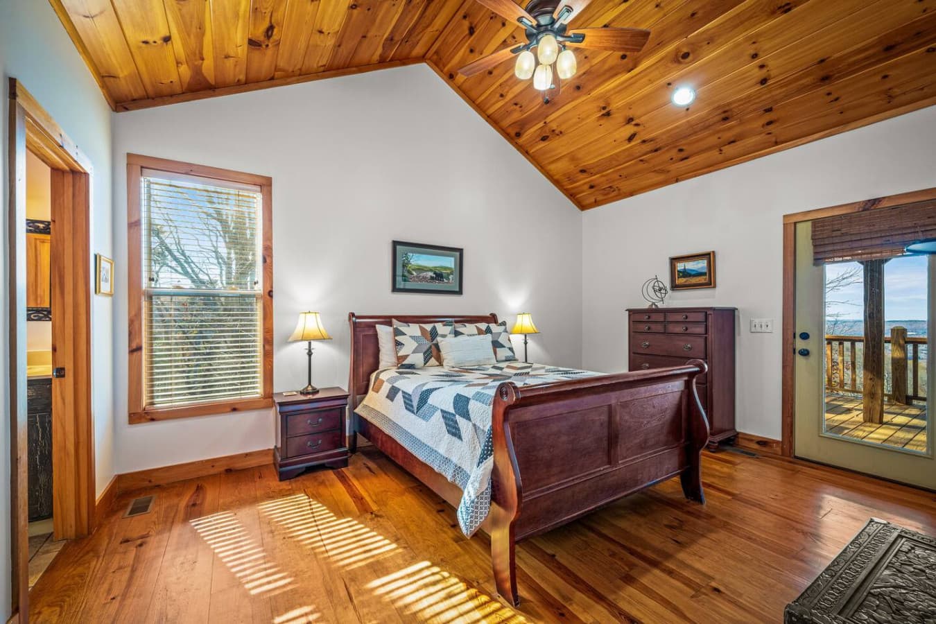 Warm and inviting, this bedroom features warm wood accents, soft lighting, and a comfortable queen bed. Vaulted ceilings and porch access create an airy, peaceful retreat perfect for relaxation.