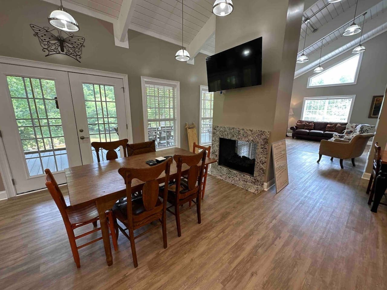 Spacious dining nook seamlessly connected to the kitchen, highlighted by high ceilings, wood floors, and French doors that open to the outdoors. The warm tones and simple décor offer a cozy yet elegant atmosphere.