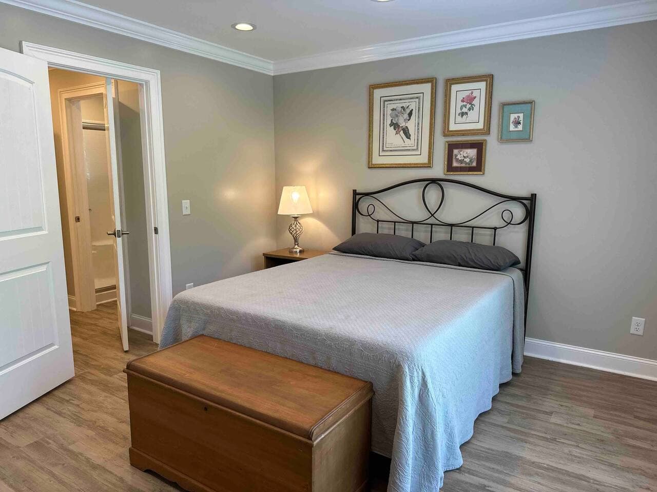 Cozy bedroom with a queen bed, soft lighting, and tasteful wall art. Features hardwood floors, neutral décor, and a private ensuite bathroom for added comfort.