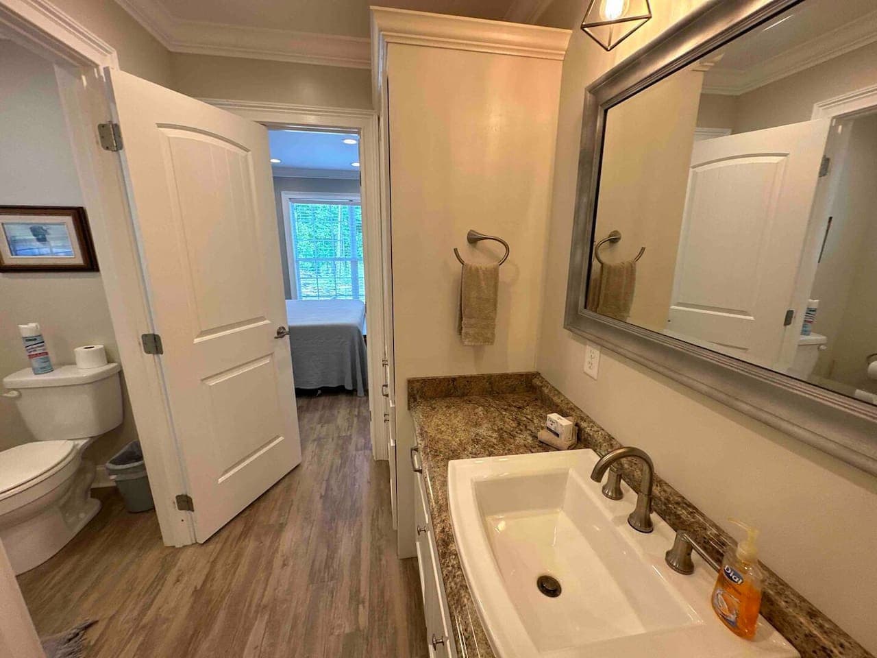 Half bathroom ensuite to Bedroom 4 featuring a granite vanity, framed mirror, and access to both the bedroom and adjoining toilet area.
