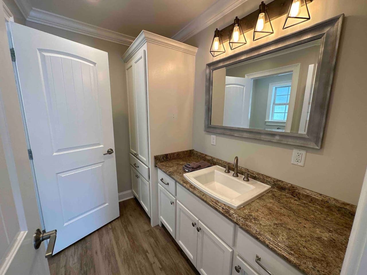 Half bathroom ensuite to Bedroom 4 featuring a granite vanity, framed mirror, and access to both the bedroom and adjoining toilet area