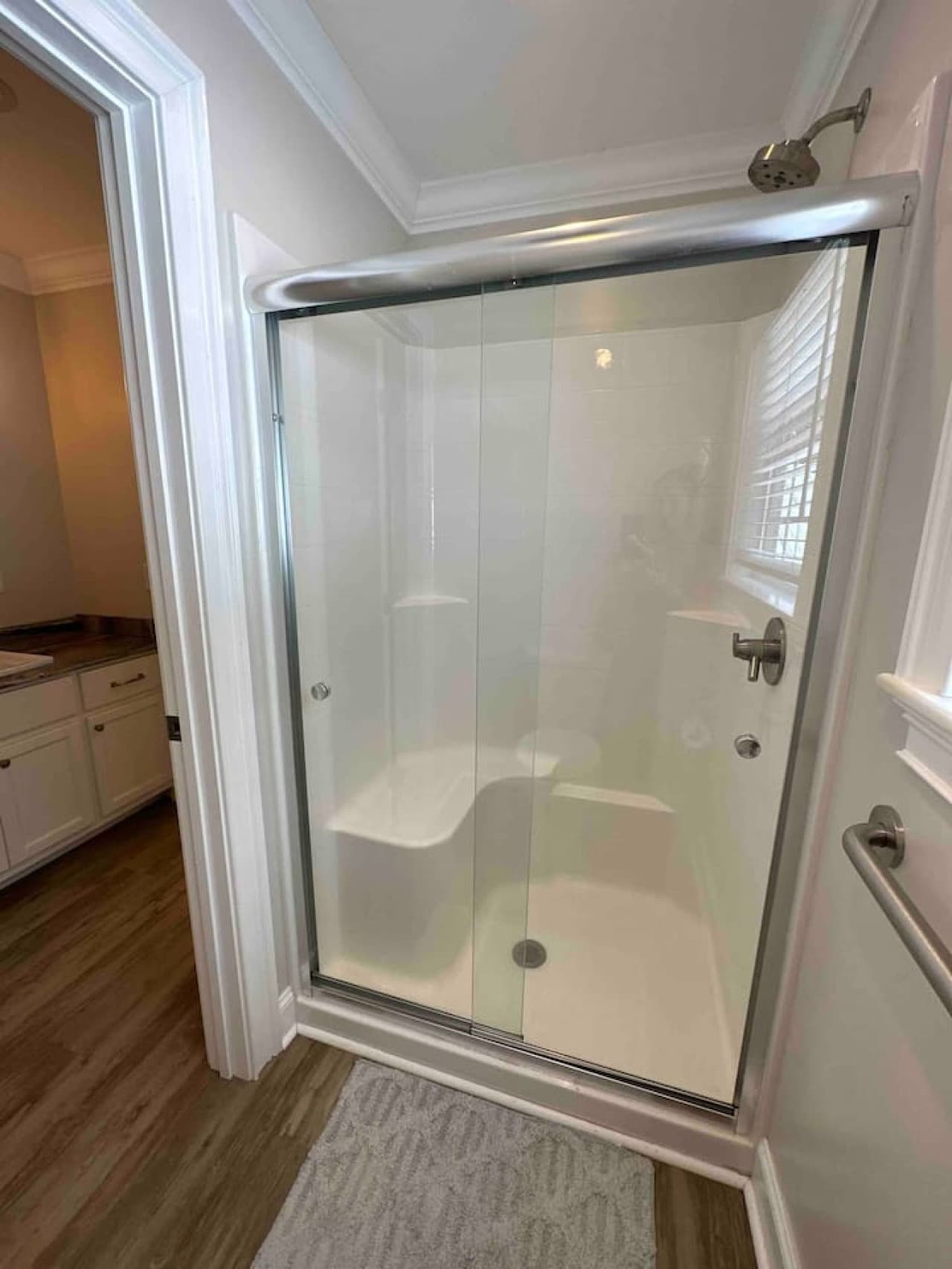 Compact and stylish bath with a sleek glass shower, window for natural light, and modern fixtures.