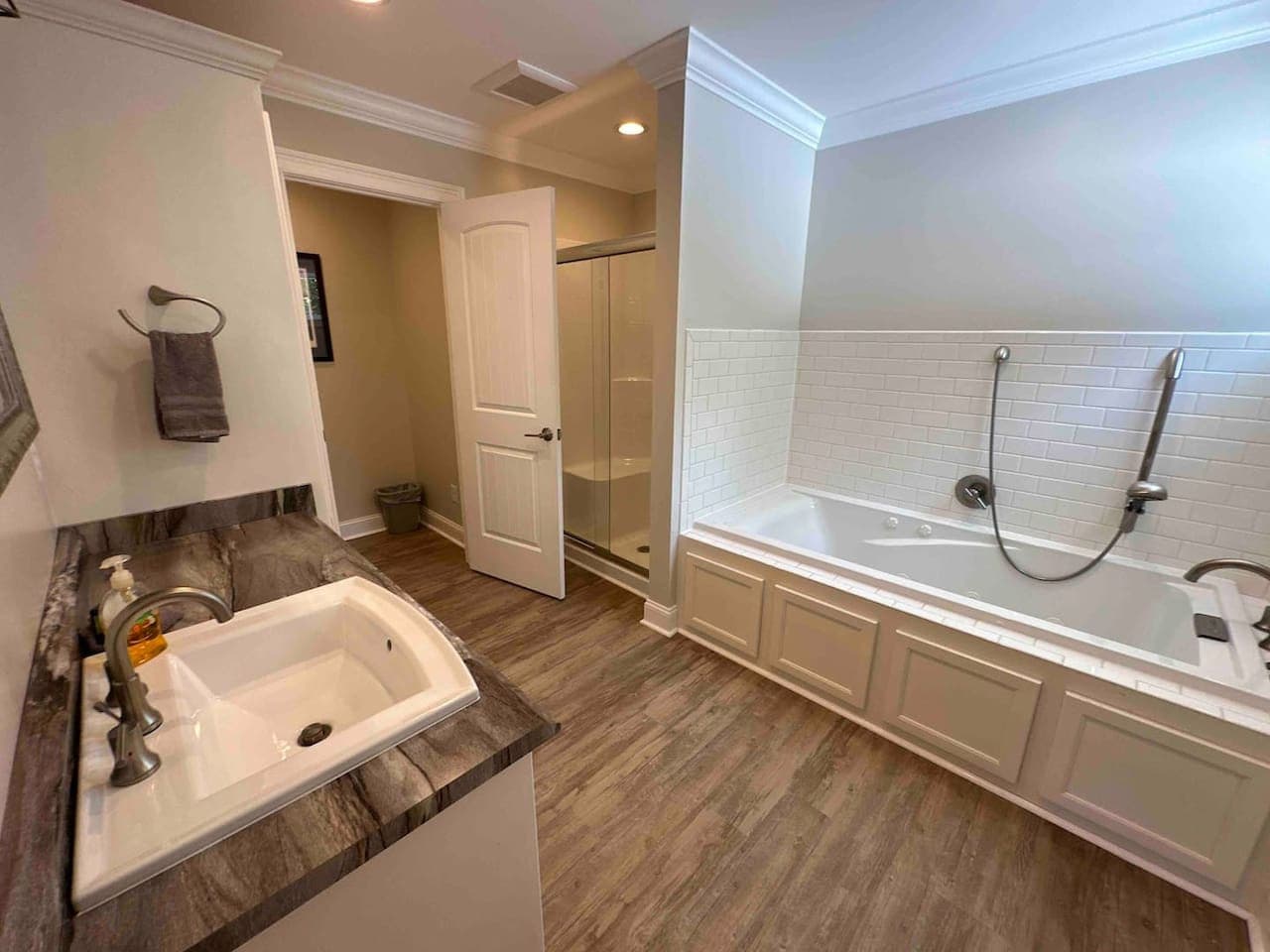 Spacious bathroom featuring a large soaking tub, glass-enclosed shower, and modern vanity with ample counter space.