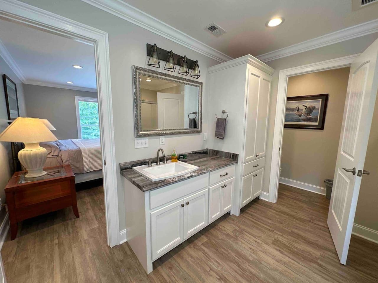 Spacious bathroom with marble-style countertop, elegant lighting, ample storage, and direct access to the adjoining bedroom.