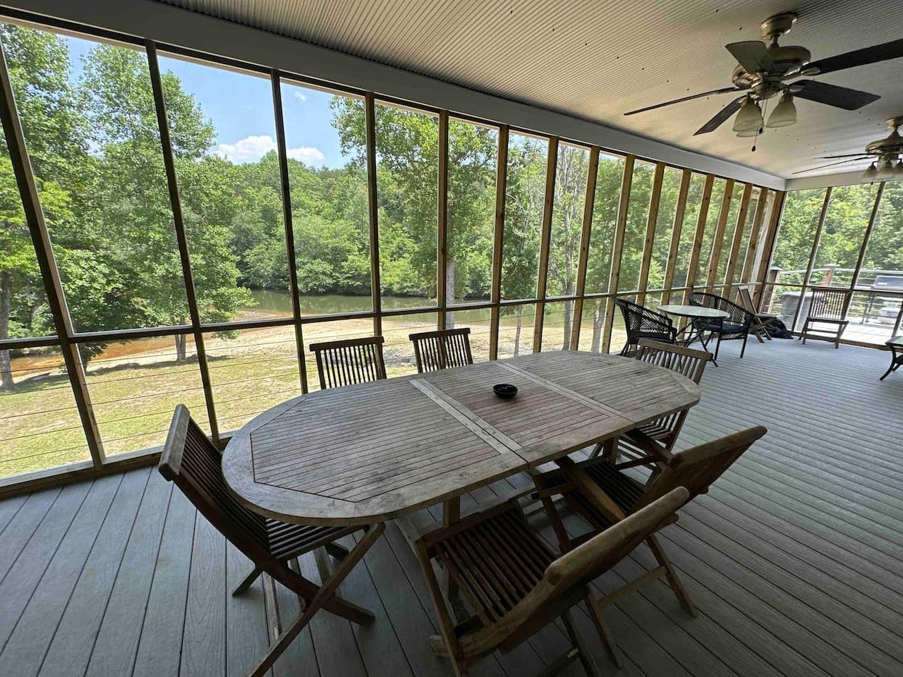 Screened-in riverside porch with a dining table—perfect for enjoying meals with a view, minus the bugs.
