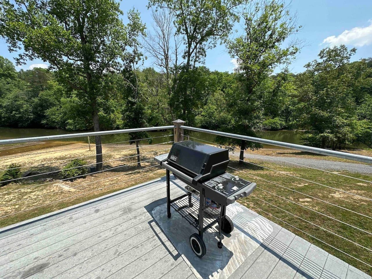 Deck area with a gas grill overlooking the river and surrounded by trees—perfect for outdoor cooking with a view.