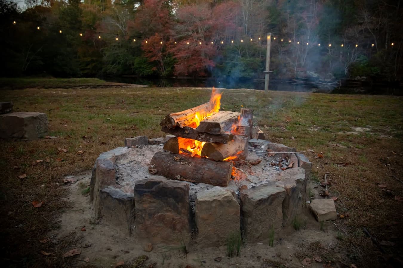 Backyard outdoor fire pit area with stone seating and a natural rock setting, surrounded by trees.