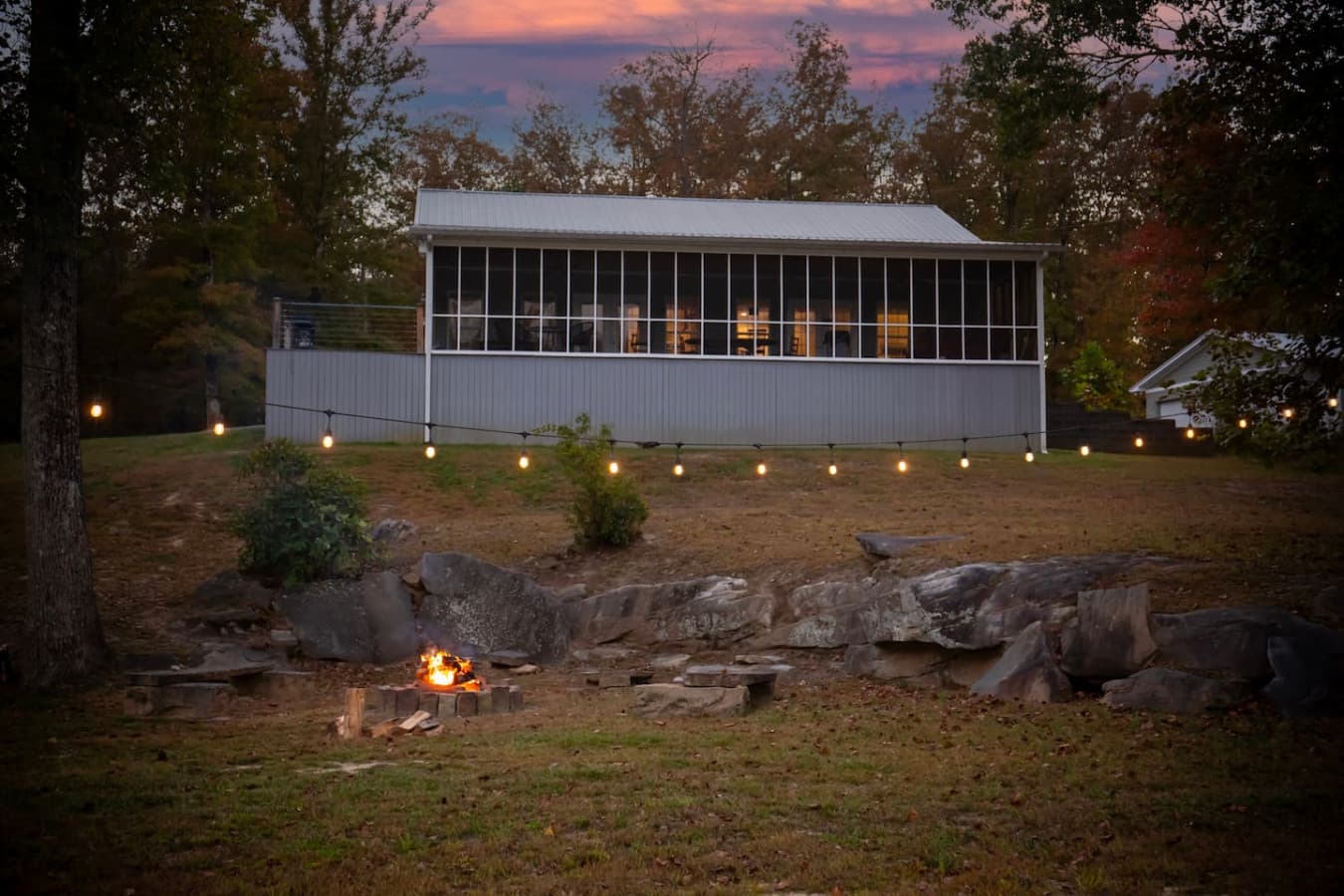 Evening view of the screened porch and backyard fire pit, beautifully lit for cozy nights outdoors.