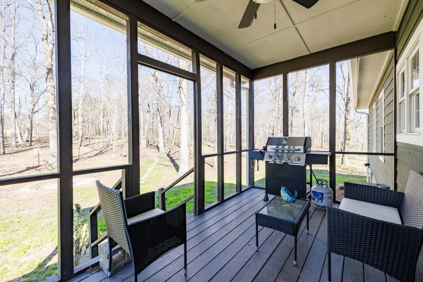 Unwind on the cozy screened-in back porch, where the scent of a sizzling grill fills the air and the sounds of nature create the perfect backdrop for a relaxing evening.