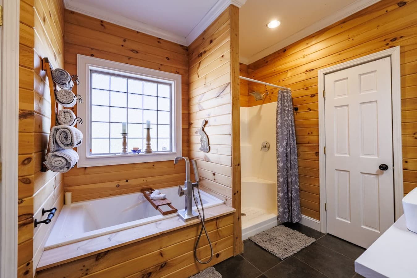Warm, wood-paneled bathroom featuring a soaking tub and walk-in shower—your private spa retreat in the cabin.