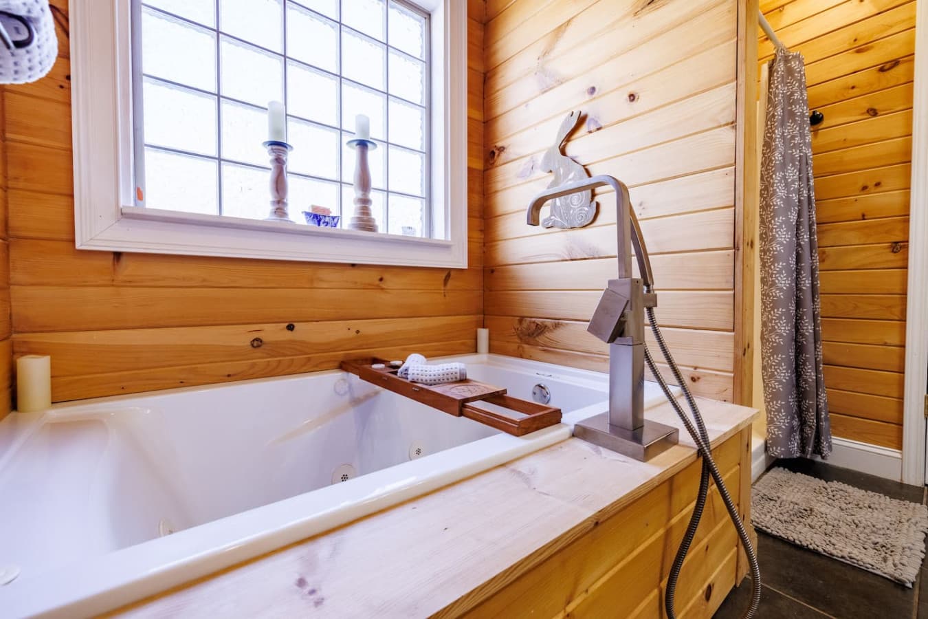 Inviting bathtub with a window view and wooden tray—perfect for a long, relaxing soak.