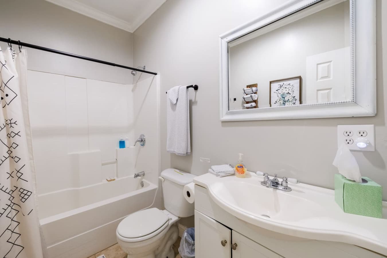 Clean and inviting bathroom with a full shower-tub combo, bright vanity, and simple, modern touches—perfect for freshening up after a day of exploring.