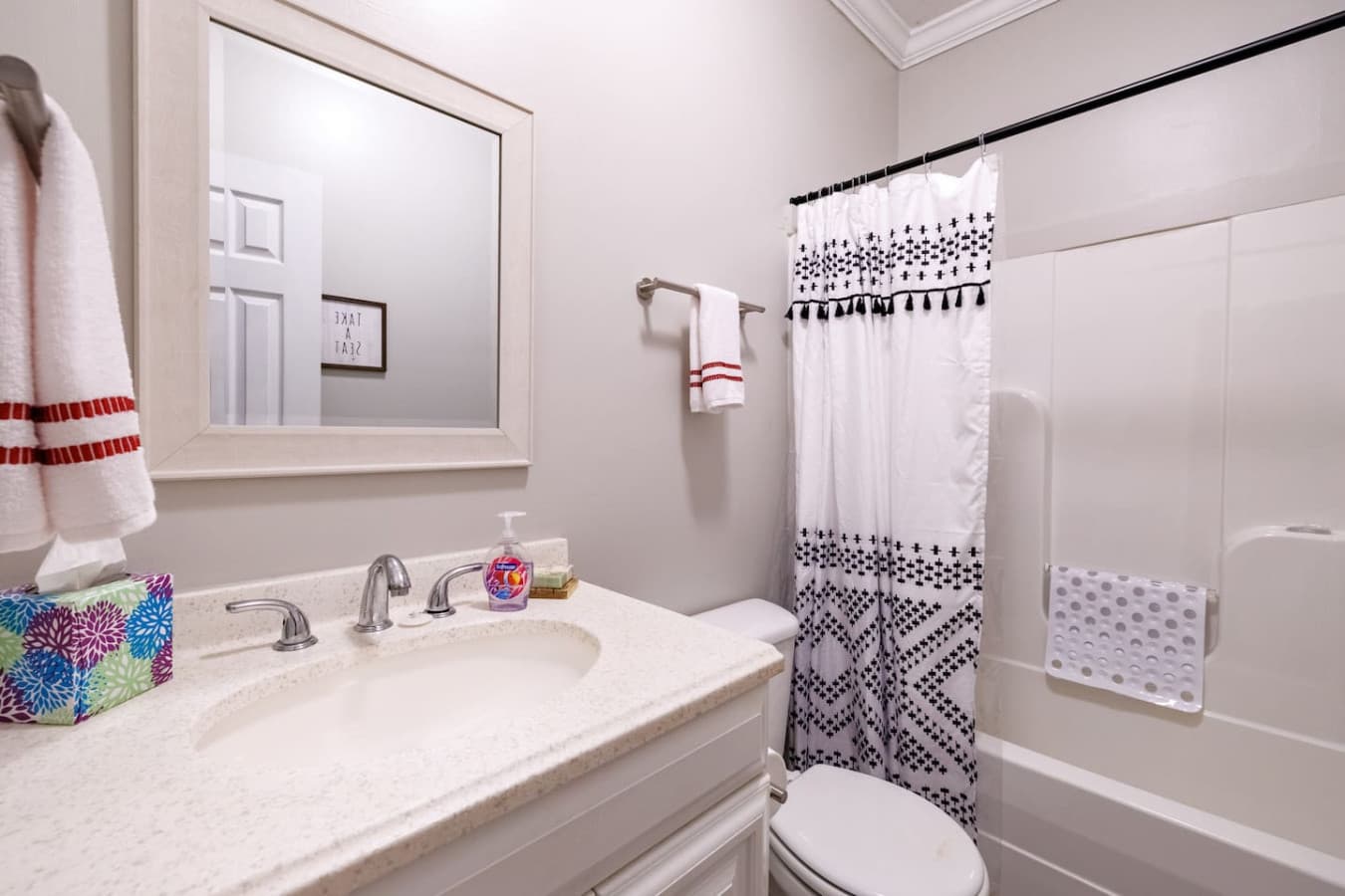 Bright and spotless bathroom with modern fixtures, a stylish patterned shower curtain, and fresh pops of color—perfect for a refreshing start or relaxing wind-down.