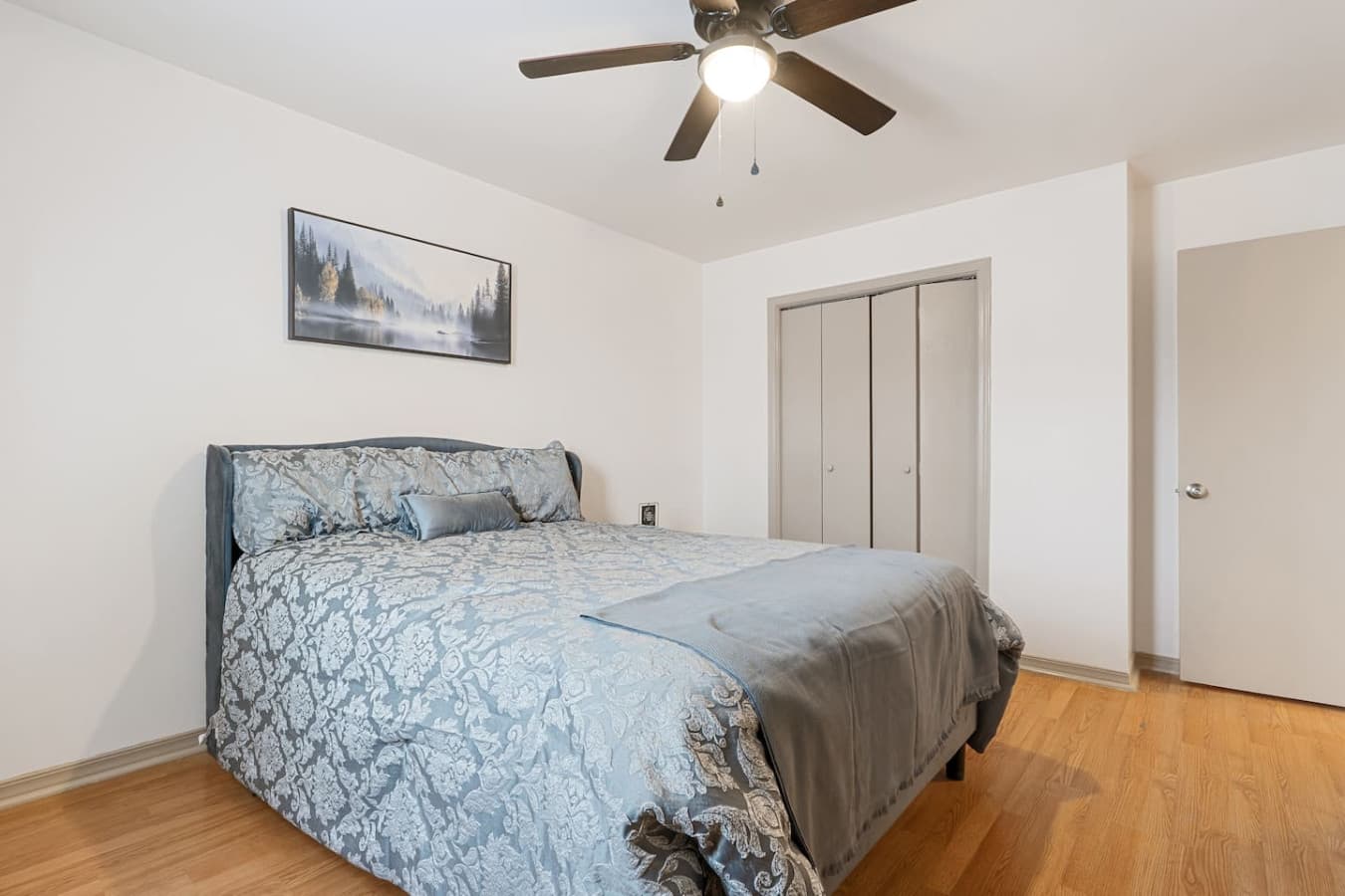 Upstairs bedroom featuring a plush queen bed, smart TV, and abundant natural light.