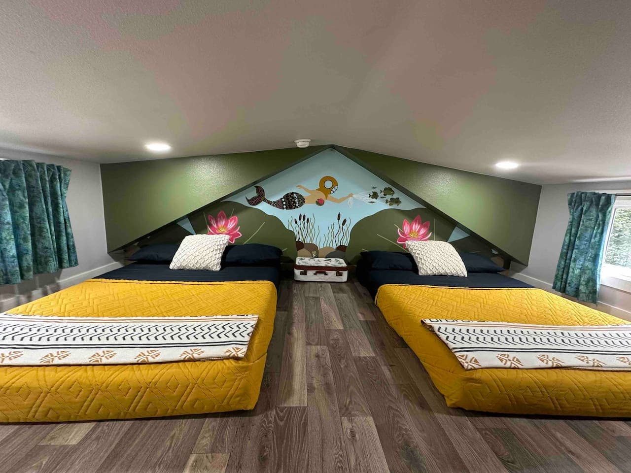 Bedroom 2 (Loft) features two full beds with linens provided, including sheets, quilts, pillows, and extra blankets. The space has a low 3–4' ceiling, making it a cozy area that’s perfect for kids.