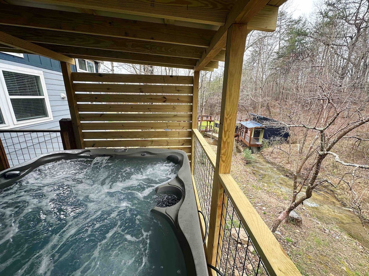 The hot tub offers stunning views of the creek and waterfall and is available for guest use for a $50 fee, providing the perfect spot to relax and unwind in nature.
