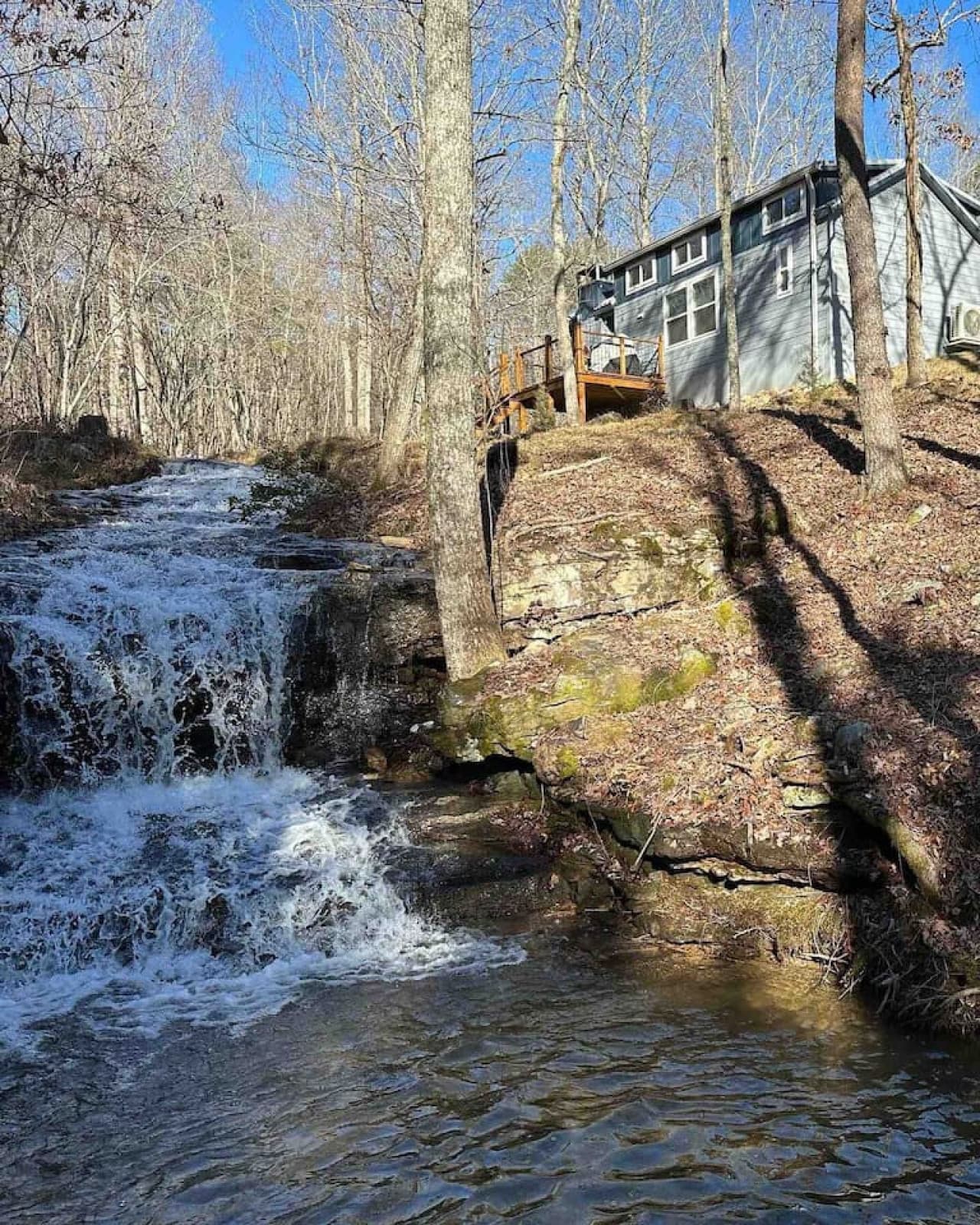 The Whimsical Waterfall Cottage is a tiny home nestled above Blueberry Falls, overlooking a serene waterfall and creek.