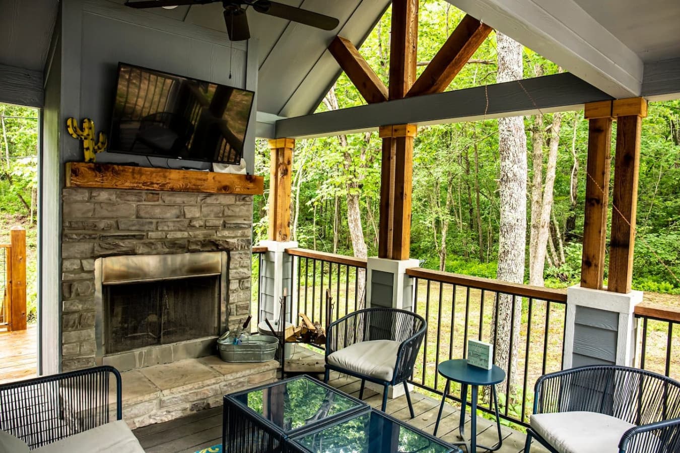 The wrap-around porch features an outdoor fireplace and a Smart TV, creating a cozy space to relax and enjoy the view.