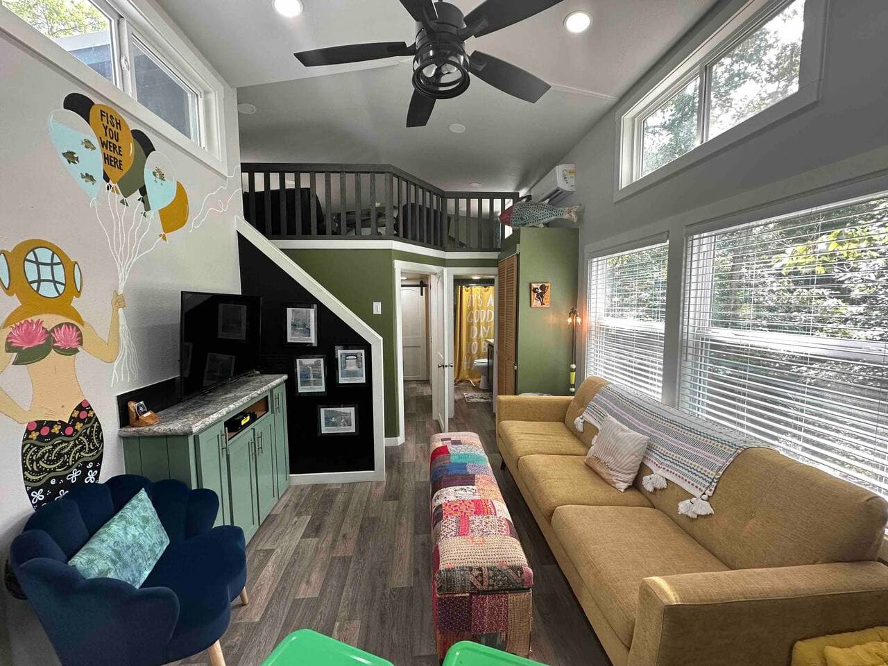 The living room features a Smart TV with streaming capabilities, a vibrant mermaid mural, and a view of the cozy loft above.