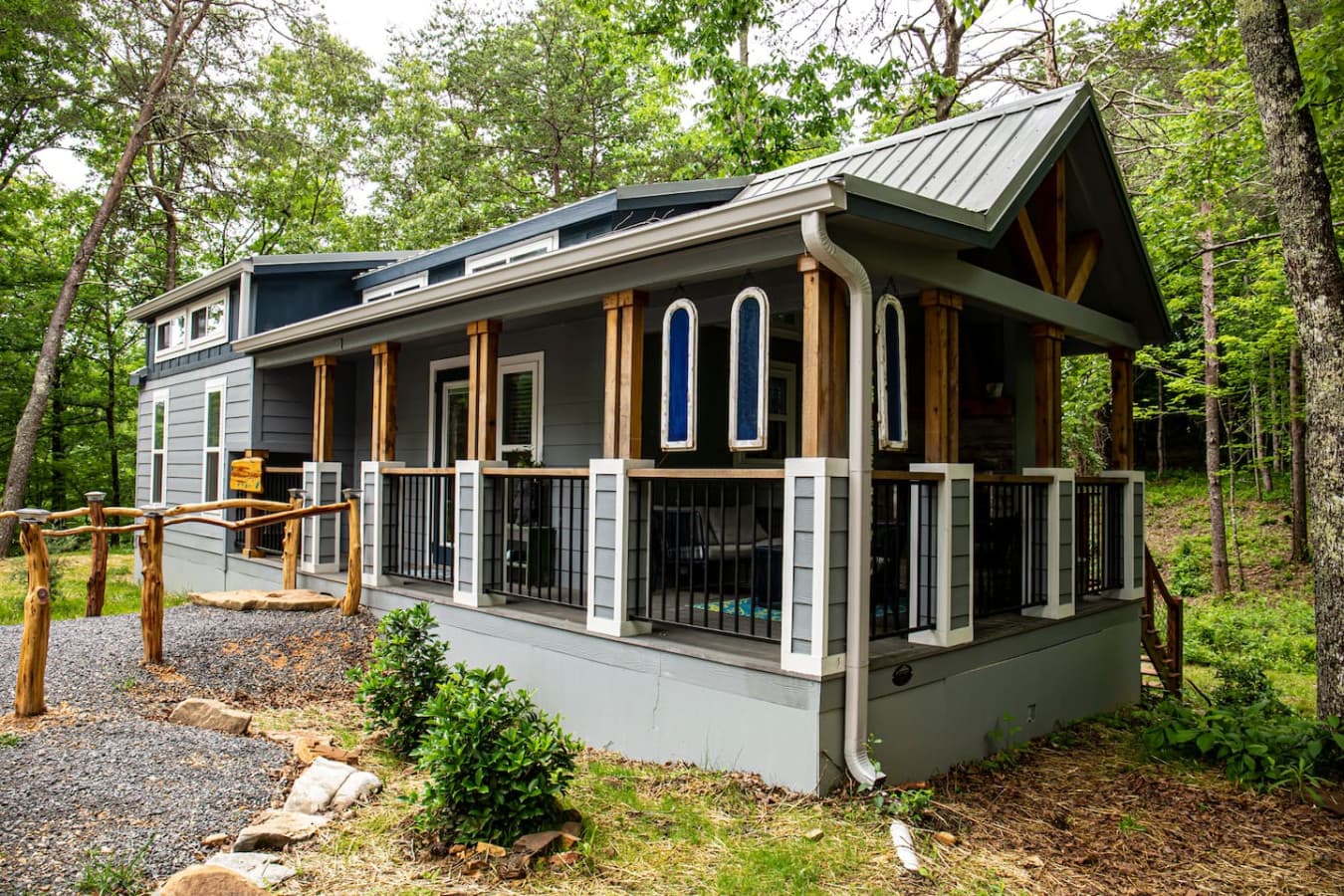 The Whimsical Waterfall Cottage is a unique tiny home perched above a creek and waterfall, offering a peaceful retreat surrounded by nature’s beauty.