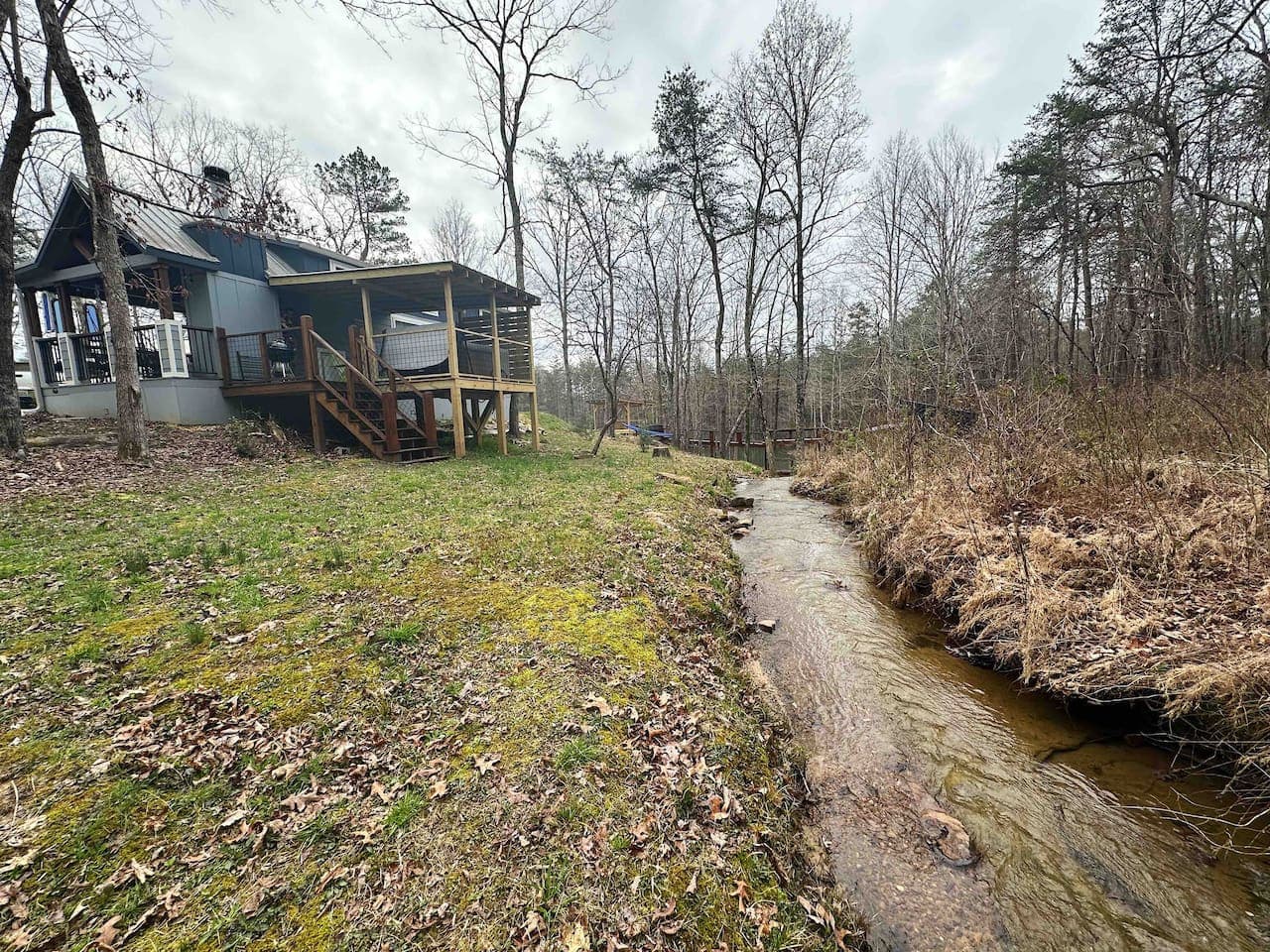 A serene creek runs just behind the cottage, offering a peaceful natural backdrop.