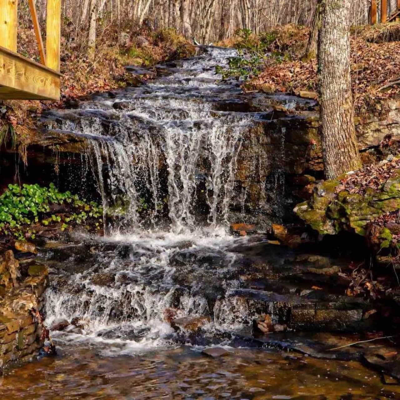The waterfall flows just below the Whimsical Waterfall Cottage, offering soothing sounds and a picturesque view.