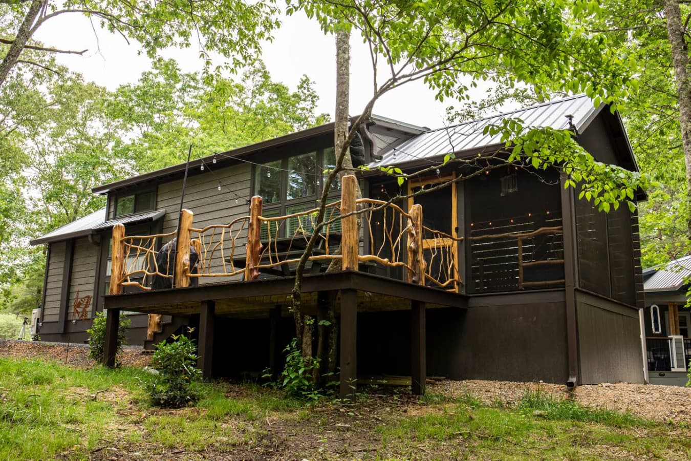 The Crooked Tree Cabin has a screened in porch with day bed and rockers and an uncovered porch with picnic table and grill.