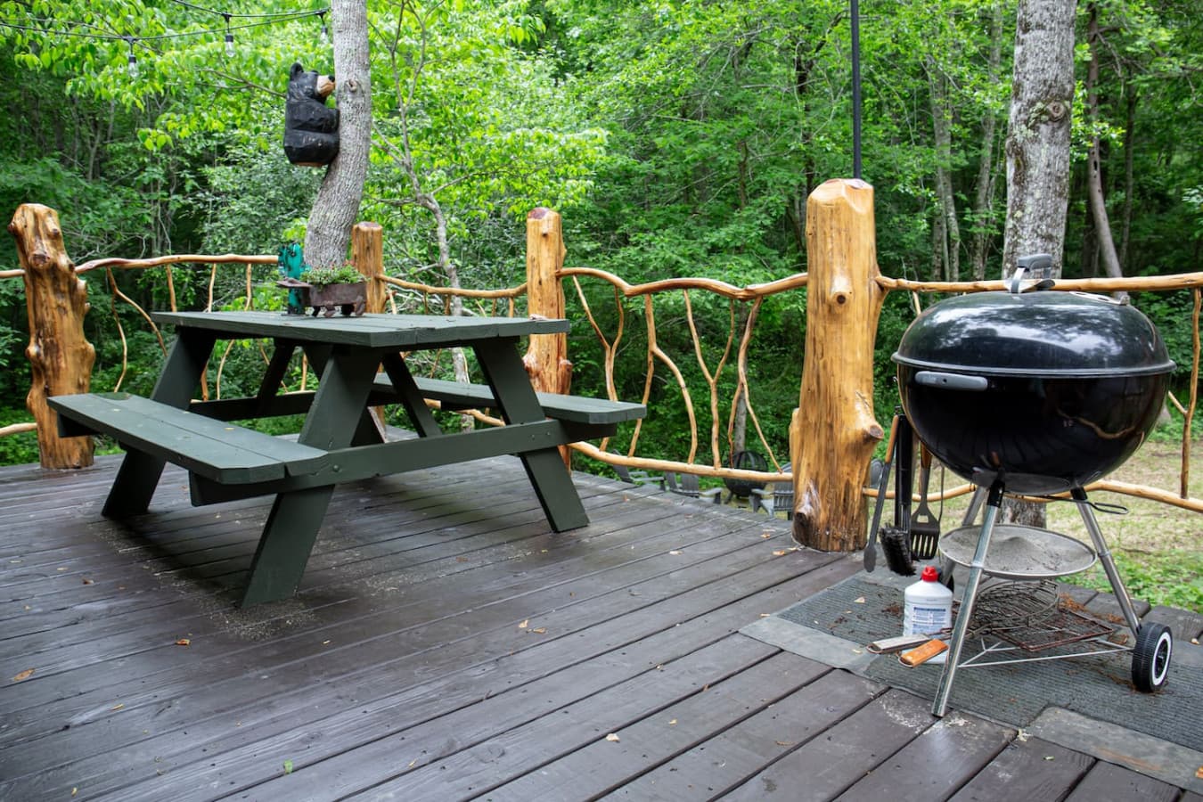 The uncovered porch has a charcoal grill and a picnic table. String lights hang above.