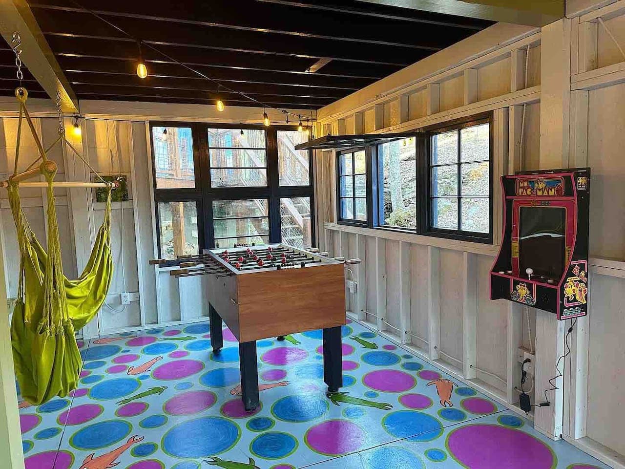 The shared game room offers foosball, Pac-Man, a TV with DVD and PlayStation, crafts, and hanging chairs for relaxation and fun.