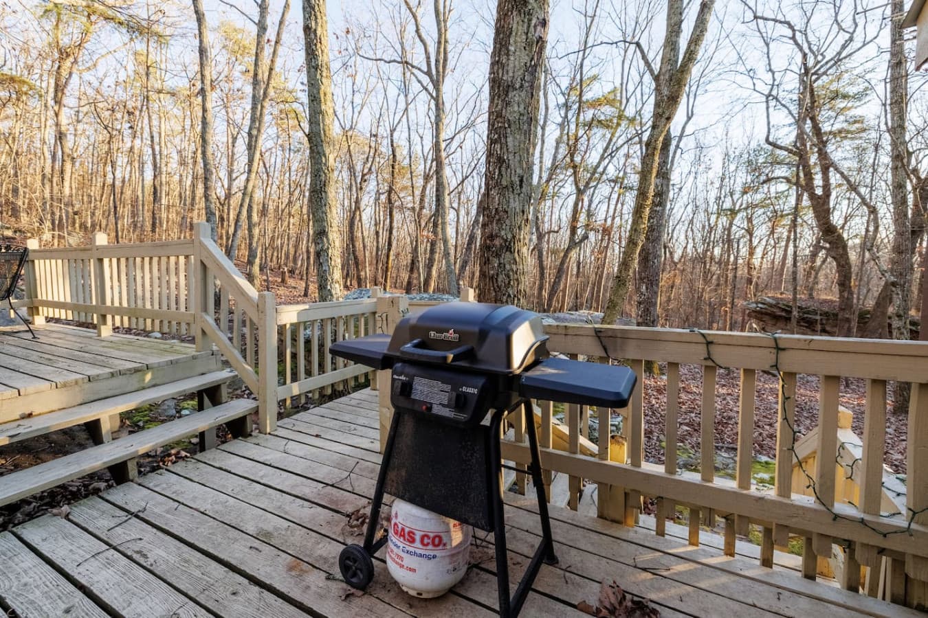 Rock Haven – Large back porch with a grill and seating surrounded by trees.