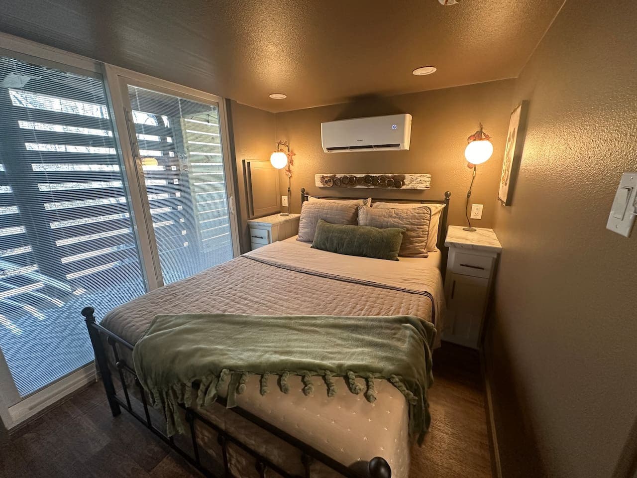 The master bedroom on the main floor features a queen bed with linens provided, a dresser and closet with hangers, and sliding glass doors leading to the covered back porch and hot tub.